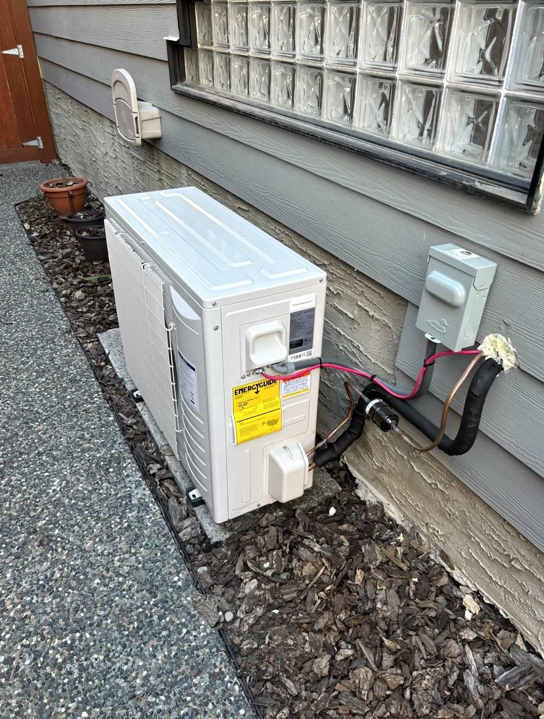 Outdoor heat pump and AC condenser installed beside a Calgary home